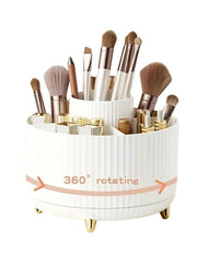 A white, five-compartment rotating makeup organizer with gold feet holding brushes and cosmetics.