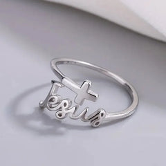 A silver-colored ring featuring the word Jesus in cursive script topped with a small cross.