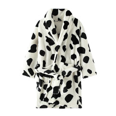 A cozy, white flannel children's bathrobe featuring a black cow-print pattern and a waist tie.