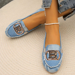 Light blue denim loafers featuring a prominent gold-tone letter B emblem on the front.