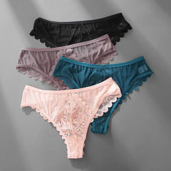 Four pairs of low-waist lace thongs in black, purple, teal, and pink arranged on a gray surface.