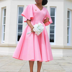 A woman wears a pink mid-calf A-line dress with a V-neck and butterfly sleeves.