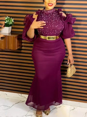 A woman wears a purple ankle-length evening gown with a high collar, cold shoulders, and a belt.