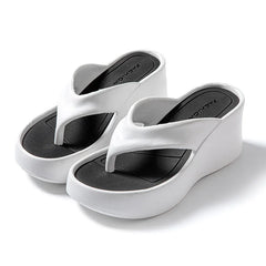 A pair of white platform wedge flip-flops with black insoles and a thick EVA sole.