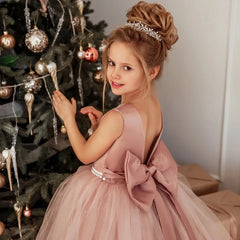A girl wears a dusty pink floor-length ball gown with a pearl belt and a large back bow.