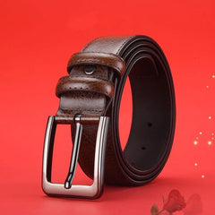 A brown textured leather belt with a silver alloy needle buckle against a red background.
