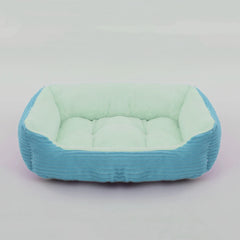 A rectangular pet bed with a blue corduroy exterior and a soft, light green plush interior.