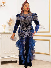 A woman wears a long-sleeved navy blue velvet mermaid gown with crystal embellishments and ruffles.