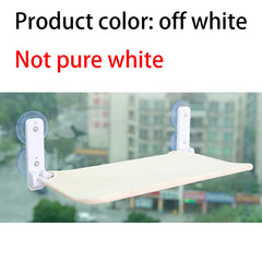 An off-white cat hammock with suction cups mounted on a window.
