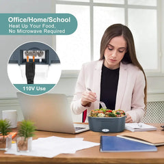 A woman eats from a portable electric lunch box plugged into a wall outlet at her desk.
