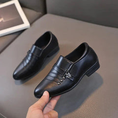 A pair of black leather loafers for boys featuring a decorative metal buckle and stitched details.
