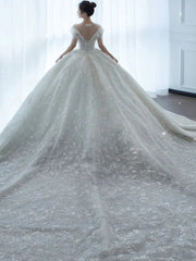 A white ball gown wedding dress with a sweetheart neckline, crystal beading, and a long train.