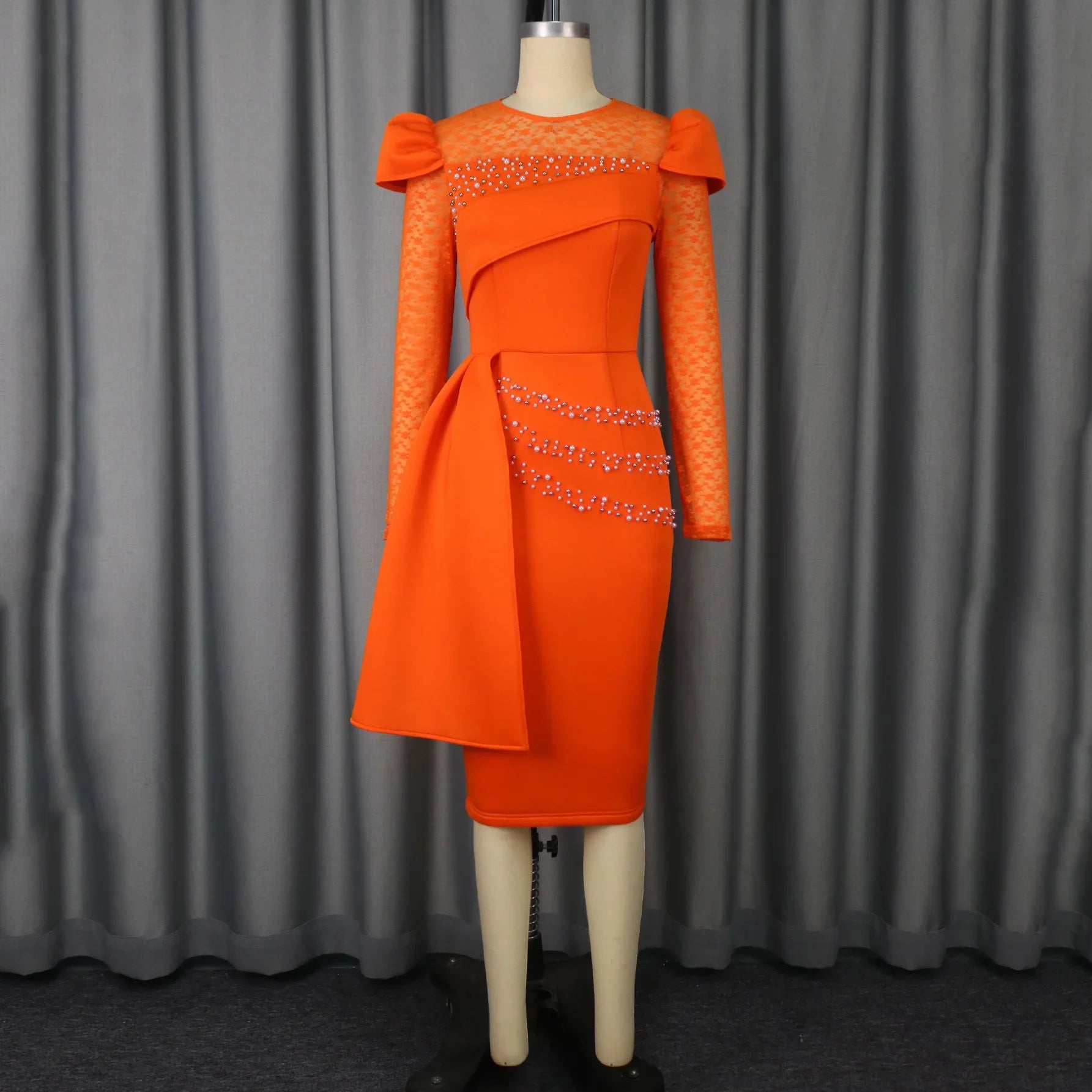 An orange midi sheath dress with lace sleeves, beaded accents, and a side drape detail.