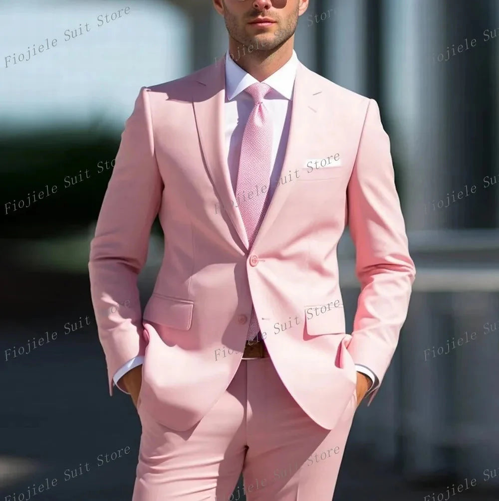 A man wears a light pink two-piece suit with a white shirt and matching tie.