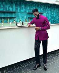 A man wears a magenta mandarin-collar jacket with black trousers and black tassel loafers.