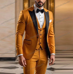 A man wears a mustard yellow three-piece suit with a black lapel, white shirt, and black bow tie.