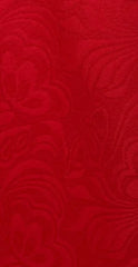 A close-up view of red fabric featuring a subtle, tone-on-tone floral damask pattern.