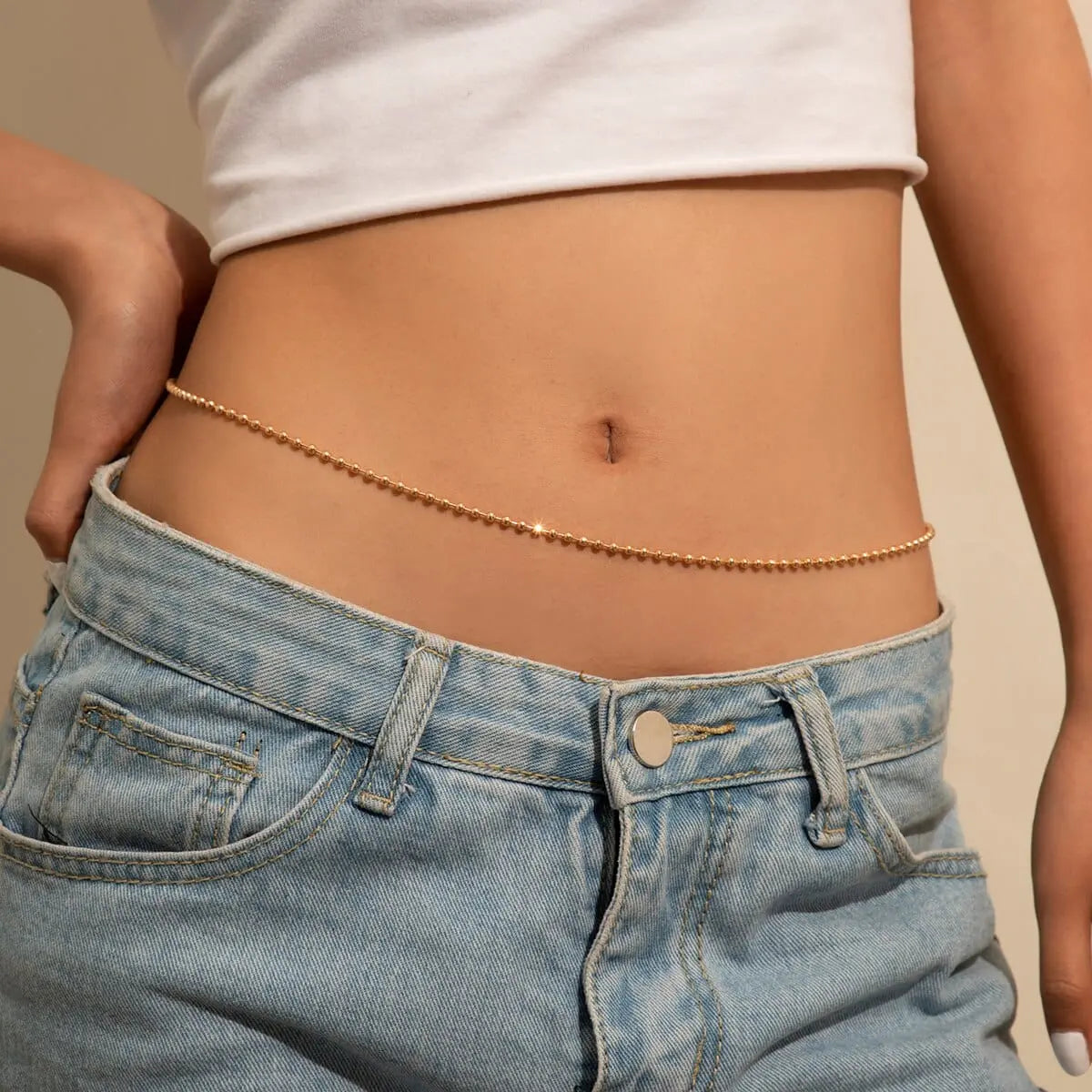 A person wears light blue jeans and a white crop top, showcasing the Sexy Vintage Aesthetic Belly Chain Thin Beads Link Body Chain Belt—stylish Y2K streetwear body jewelry for a chic summer fashion statement.
