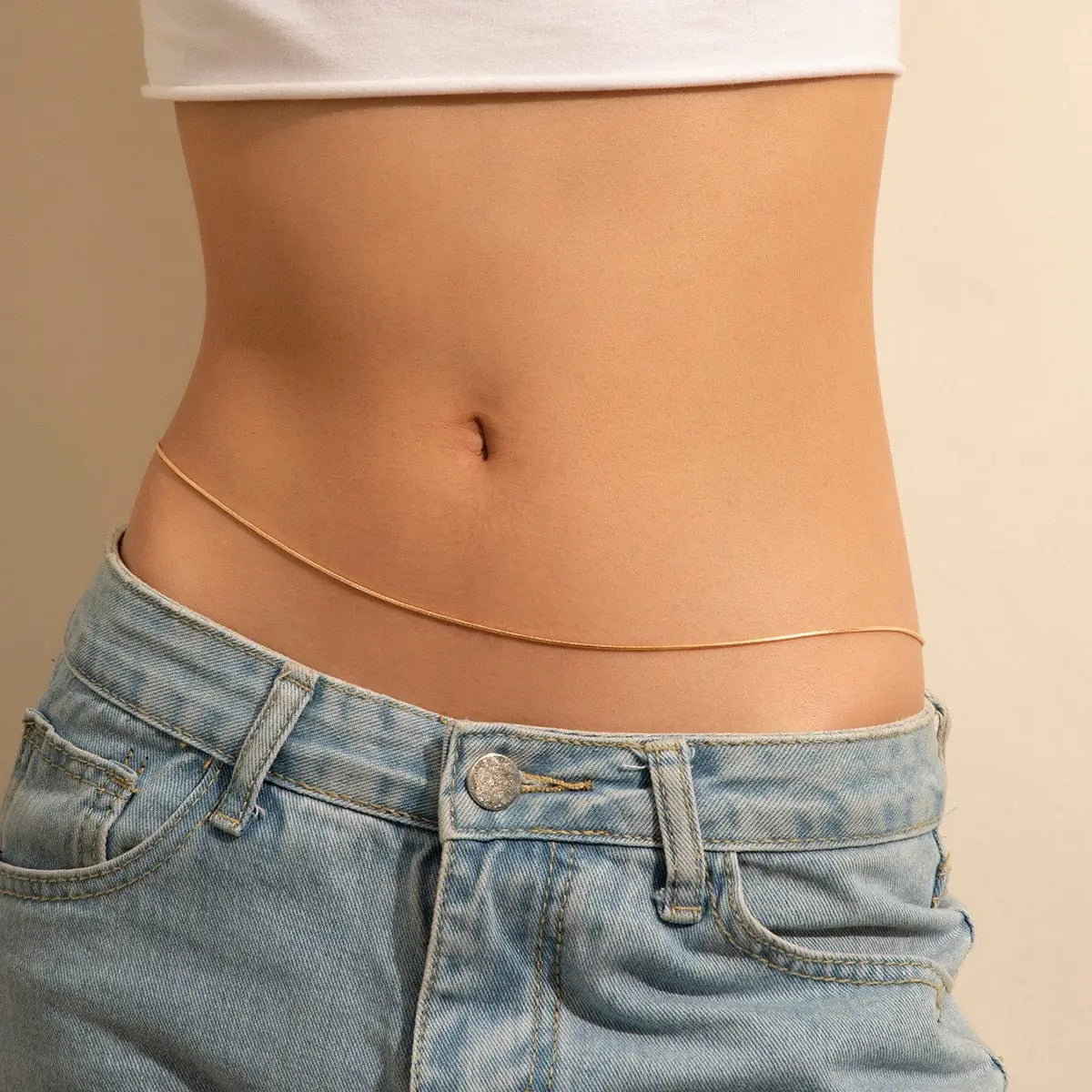 A close-up of a person wearing light blue jeans, a white crop top, and the Sexy Vintage Aesthetic Belly Chain Thin Beads Link Waist Chain Belt, showcasing trendy Y2K streetwear summer women fashion body jewelry.