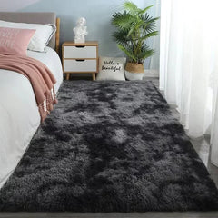 A rectangular, plush gray area rug with a soft, shaggy texture placed in a bedroom.