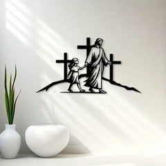 A black metal wall art sculpture depicting Jesus walking with a child in front of three crosses.