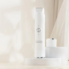 A white electric hair remover with a detachable head stands on a speckled stone pedestal.