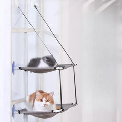 A double-decker cat hammock with suction cups mounted to a window, featuring two resting cats.