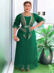 A woman wears a long-sleeved emerald green pleated gown with beaded bodice detailing and a belt.