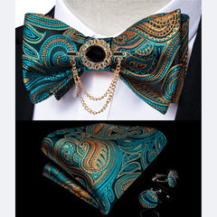 A teal and gold paisley bow tie set with a brooch, pocket square, and matching cufflinks.