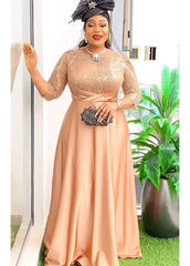 A woman wears a long-sleeved, champagne-colored maxi dress with a sequined bodice and satin skirt.
