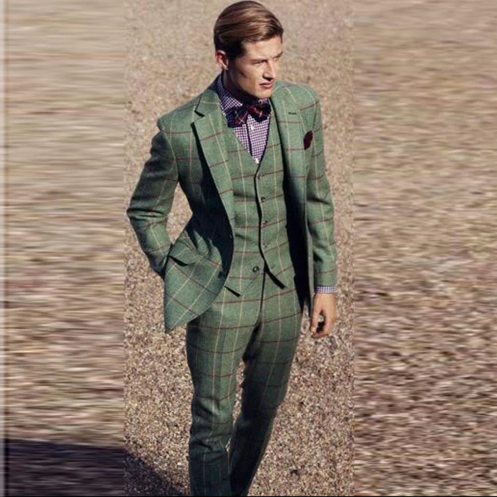 A man wears a green three-piece suit with a brown windowpane check pattern and a bow tie.