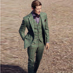 A man wears a green three-piece suit with a brown windowpane check pattern and a bow tie.