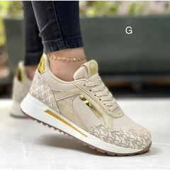 A beige and gold designer-style sneaker with a patterned upper and a low wedge sole.