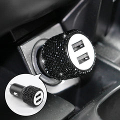 A dual USB car charger decorated with black rhinestones, shown plugged into a vehicle console.