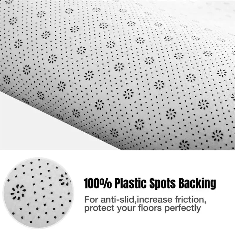 The underside of a rug featuring a white fabric backing with a pattern of small black plastic dots.