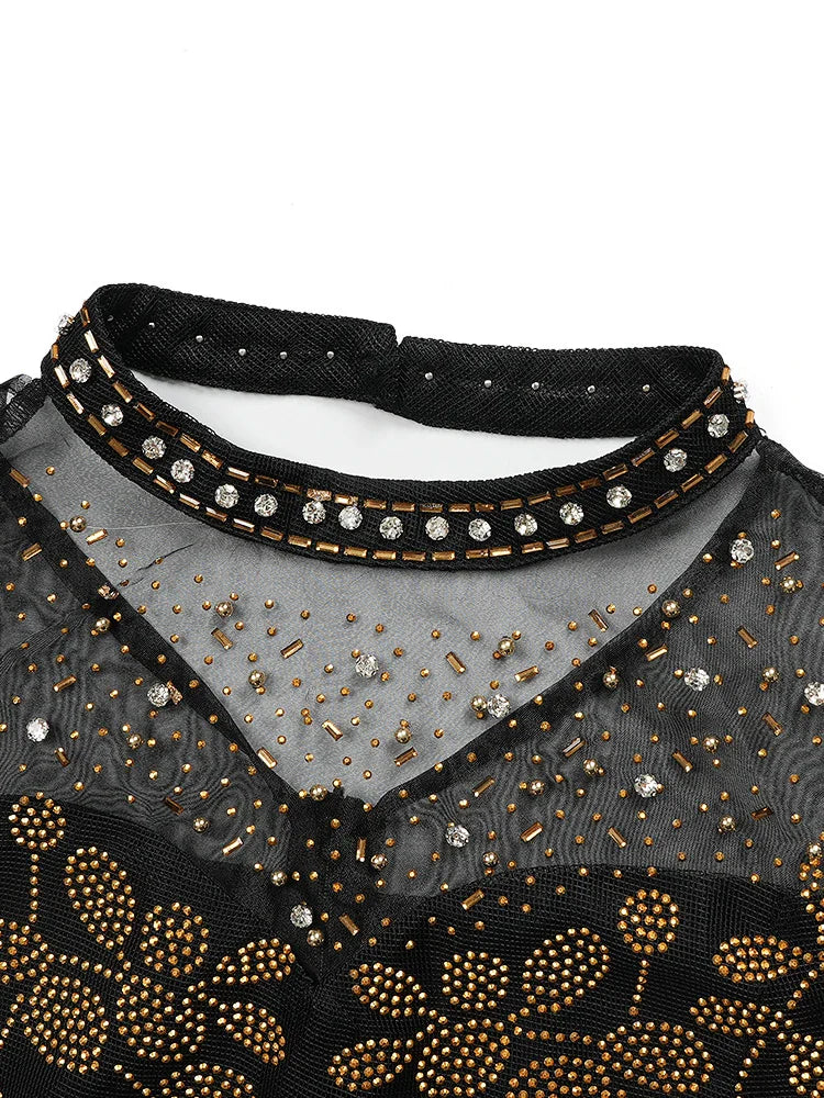 A black mesh evening gown featuring a high neckline adorned with gold beads and clear crystals.