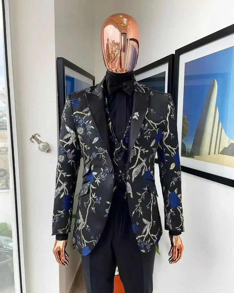 A three-piece black suit featuring a floral jacquard blazer, matching vest, and solid trousers.