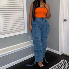 A woman wears high-waisted blue denim cargo pants with multiple pockets and tie-hem details.