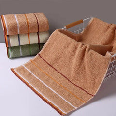 A stack of three folded cotton towels sits next to a matching towel draped over a wire basket.