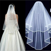 A two-layer white tulle wedding veil with a ribbon edge and an attached comb.