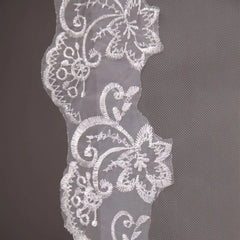 A white two-layer bridal veil featuring delicate floral lace embroidery along the edges.