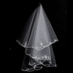 A two-layer white tulle wedding veil featuring a ribbon edge with decorative looped embroidery.