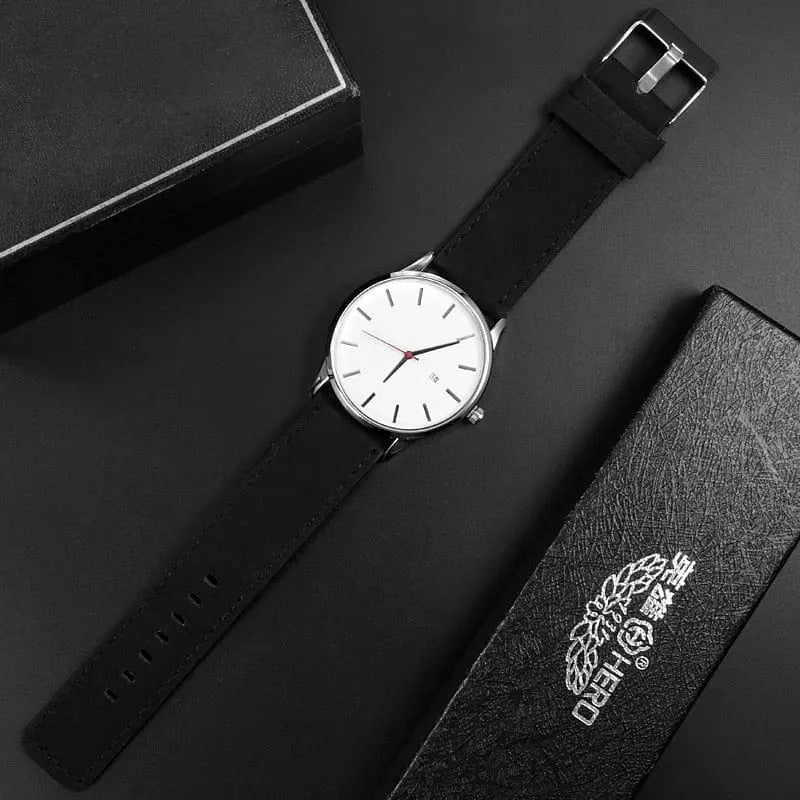 The Simple Men Quartz Watch, featuring a white face, thin black hour markers, and a black leather strap, is displayed diagonally on a dark surface beside two black watch boxes, one marked with Chinese characters.