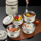A set of stackable stainless steel bento lunch boxes with lids and a matching carrying bag.