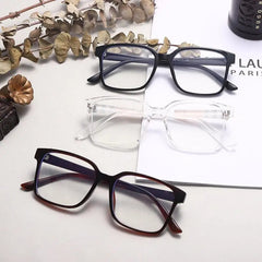 Three pairs of TR90 Retro Square Anti Blue Light Optical Glasses Frames in black, clear, and dark brown are arranged on a surface with dried leaves. Styles include cat eye and metal frames, ideal for office or computer use.