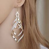 Gold-toned drop earrings featuring a twisted diamond shape with a frosted, glittery texture.