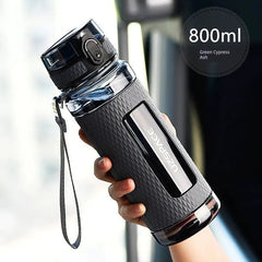 A hand holds an 800ml black Uzspace sports water bottle with a textured grip and a locking lid.