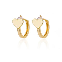 A pair of gold-toned hoop earrings featuring a small heart charm and a clear stone accent.