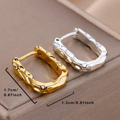 Two U-shaped hoop earrings with a textured, organic surface in gold and silver tones.