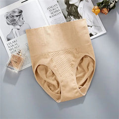 A pair of Underwear Bragas Fajas Women Shaper Thong Bodyshaper Nude Low High Waist Pant Tummy Tuck Shapewear Panties is shown on a gray surface, next to a perfume bottle, white magazine, and yellow dried flowers.